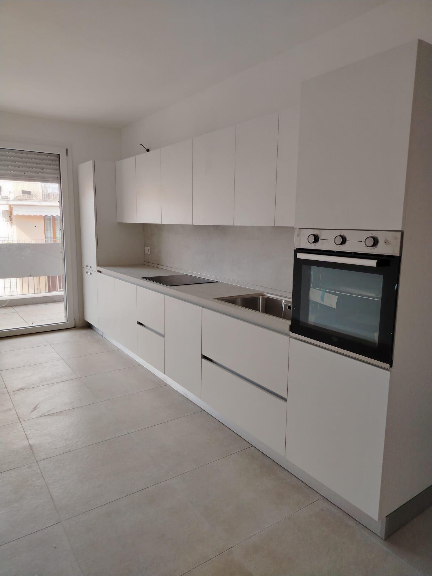 Cucina lineare bianca minimal con forno e piano induzione